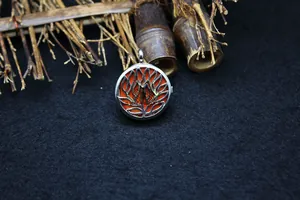 Detailed view of a silver-toned circular locket pendant with an intricate lotus cutout