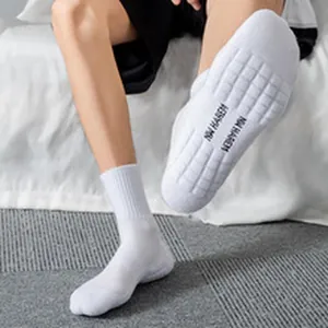Detailed view of white cotton crew socks with textured anti-slip sole and logo