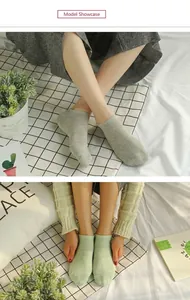 Model wearing grey and light green low-cut invisible cotton socks on a white bed sheet