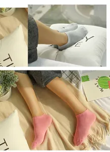 Women's pink and grey low-cut invisible boat socks shown being worn in a cozy setting