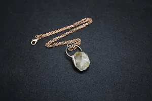 Detailed macro view of a raw green fluorite pendant on a bronze-toned metal chain