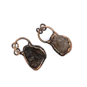 Close-up of small raw stone pendants with bronze-colored metal electroformed frames