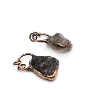 Close-up view of small raw smoky quartz stone pendants with rustic copper metal wrapping