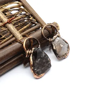 Detail view of two unique raw stone pendants featuring vintage copper wire wrapping.