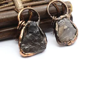 Macro view of unique raw black and clear stone pendants featuring antique copper wire wrapping