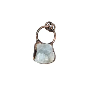 Close-up of a small raw green fluorite pendant with a rustic copper metal frame.