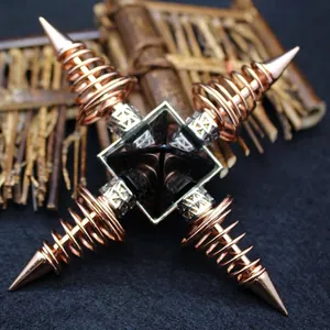 Ornate cross-shaped rose gold spring ornament with a central black pyramid crystal