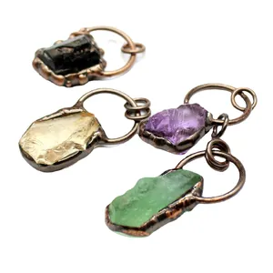 Raw fluorite and crystal stone pendants with antique bronze finish on white background
