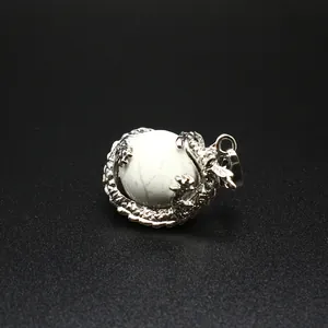 Detail van een zilveren drakenhanger die om een witte, getextureerde stenen bol wikkelt