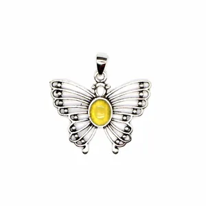 Macro detail of a silver-toned butterfly pendant featuring a translucent yellow stone center