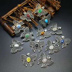 Vintage silver butterfly pendants with various natural stones on rustic bamboo background