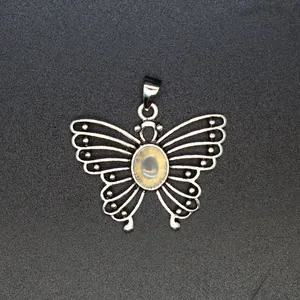 Macro view of antique silver butterfly pendant with natural stone inlay and hollow wing details