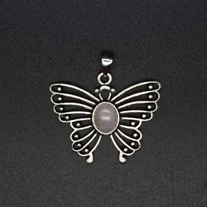 Close-up of a vintage silver butterfly pendant with an oval pink stone centerpiece.