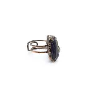 Vista dettagliata di un anello in rame medievale con pietra grezza di fluorite viola.