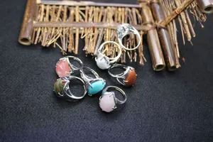 Detailed view of multiple teardrop natural stone open rings with silver flame settings.