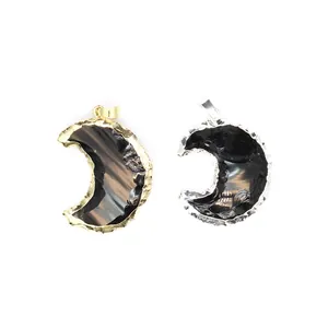 Detail view of two crescent moon-shaped obsidian pendants with gold and silver frames.