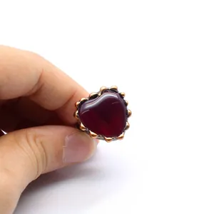 Primo piano di un anello vintage a forma di cuore con agata rossa su fascia in rame