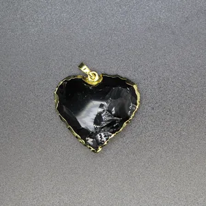 Detailed macro shot of a heart-shaped black stone pendant with a jagged gold edge finish.