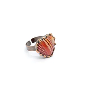 Dettaglio di un anello a cuore vintage con agata arancione striata e fascia regolabile