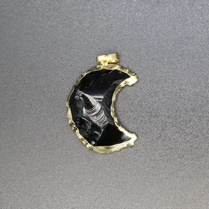 Close-up detail of a minimalist black crescent moon pendant with textured gold edging