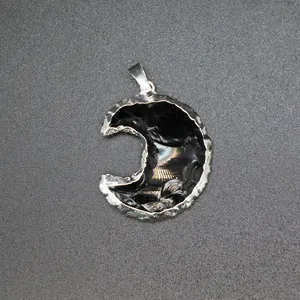 Close-up of a crescent moon pendant featuring black obsidian stone and silver edges