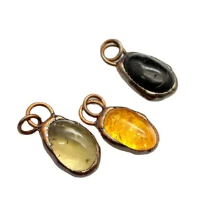 Three irregular raw stone pendants with copper wrap in citrine, clear, and black colors.