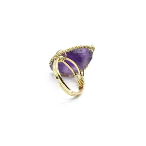 Detail view of a vintage purple raw stone ring with gold wire wrapping and adjustable band