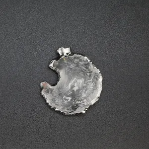 Macro detail of crescent moon shaped clear crystal pendant with silver plated textured edge