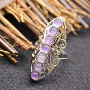 Exaggerated silver-tone adjustable ring featuring ornate metalwork and purple stones.