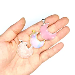 Detailed view of three colorful crescent moon pendants held in a hand for size comparison