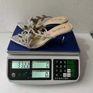 Sabot argento con tacco e foglie di strass pesati a 332,2 g su una bilancia digitale