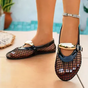 Detailed close-up of black fishnet hollow flat sandals with golden metal buckle decoration
