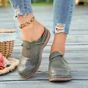 Close-up of vintage olive green wedge mules with laser-cut floral patterns