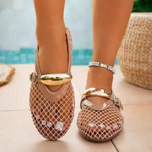 Close-up of beige fishnet hollow out flat sandals with gold metal buckle detail