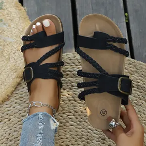Retro-Sandalen mit schwarzen geflochtenen Riemen und antiker Schnalle auf Strohmatte