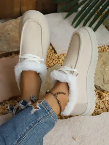 Close-up of cream corduroy winter loafers with white faux fur lining and lace-up detail