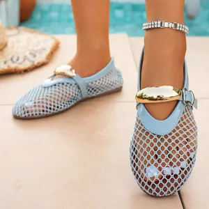 Close-up of light blue mesh flat sandals featuring a large gold metallic buckle