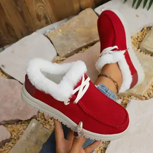 Close-up of red winter snow boots with white fur lining and lace-up details