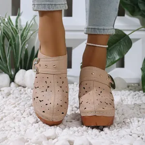 Detail view of beige laser-cut flower clog mules with chunky wood-like high heel