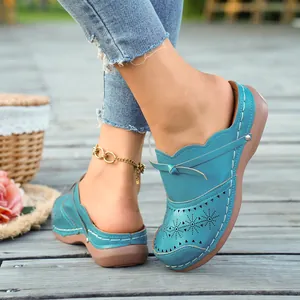 Close-up of blue retro wedge mules with hollow-out floral patterns and contrast stitching