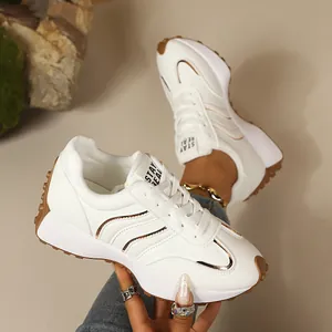 Nahaufnahme weißer Damen-Chunky-Sneaker mit brauner Gummisohle und Goldakzenten.