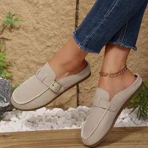Detail view of beige suede backless loafers with buckle strap and white stitching