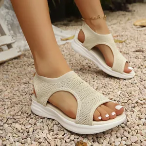 Detailopname van beige ademende gebreide platform Romeinse sandalen voor dames op grind