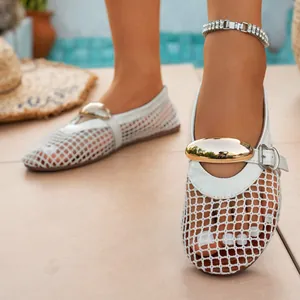 Close-up detail of stylish white mesh hollow-out flat sandals with gold ornament.