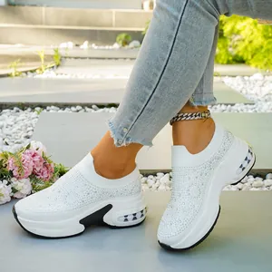 Detailansicht der weißen Damen-Keilsneaker mit funkelnden Strasssteinen auf einem Außenweg