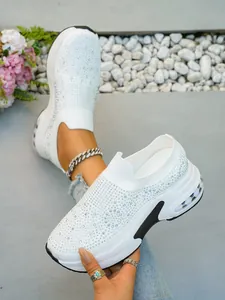 Nahaufnahme weißer Damen-Sneaker mit Strasssteinen, Keilsohle und sportlichem Design