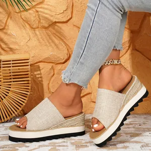 Vue détaillée de sandales compensées en toile beige avec détails en corde et semelle épaisse.