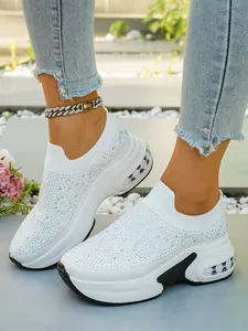Detailansicht weißer Plateau-Sneaker mit glitzernden Strasssteinen und Keilabsatz.