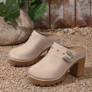 Detailed view of beige patent leather platform mules with chunky heels and gold rivets.