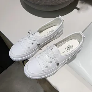 Detailed top view of minimalist white leather board sneakers with decorative laces for women